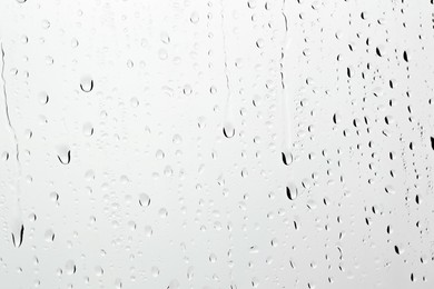 Water drops on light grey glass surface, closeup