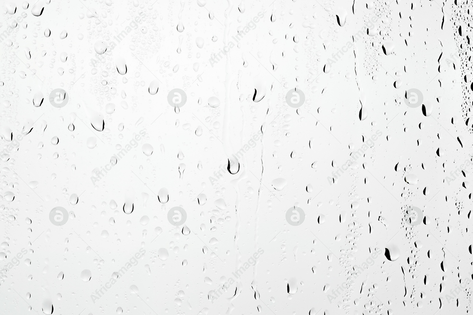 Photo of Water drops on light grey glass surface, closeup