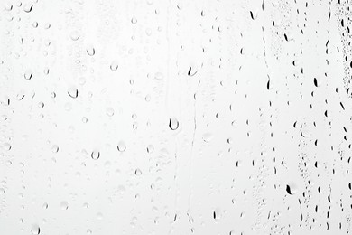 Water drops on light grey glass surface, closeup