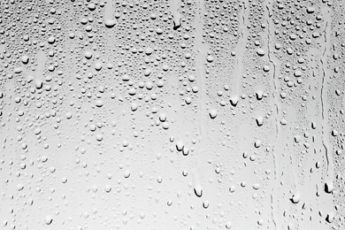 Photo of Water drops on grey glass surface, top view