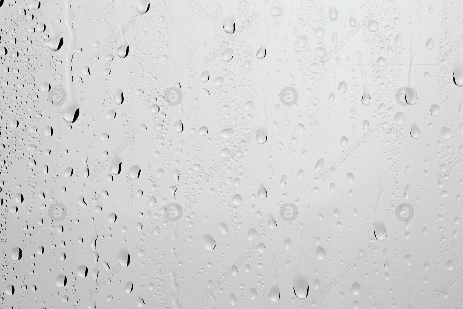 Photo of Water drops on light grey glass surface, closeup