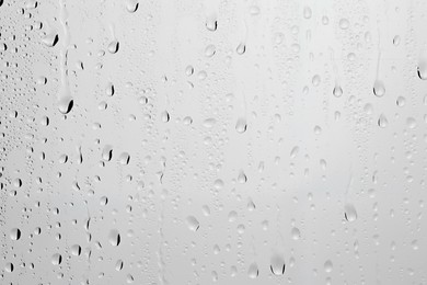 Photo of Water drops on light grey glass surface, closeup