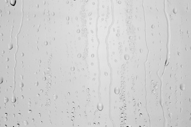 Photo of Water drops on light grey glass surface, top view