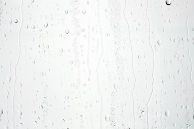 Photo of Water drops on light grey glass surface, top view