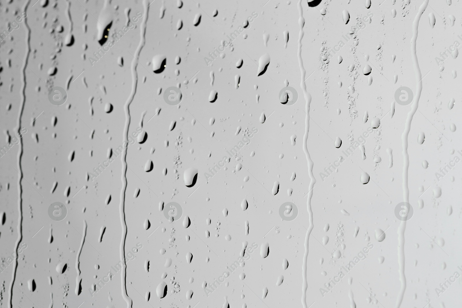 Photo of Water drops on light grey glass surface, closeup