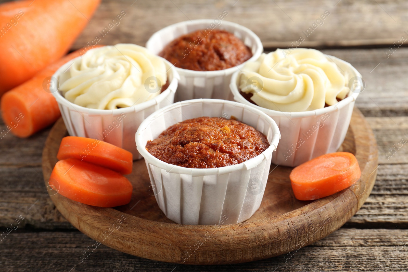 Photo of Delicious carrot muffins and fresh vegetable on wooden table, closeup