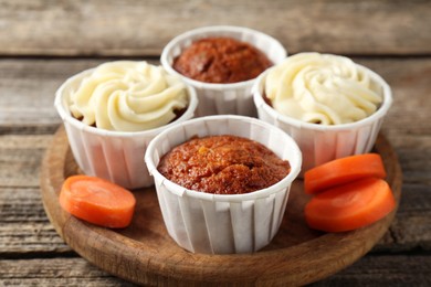 Photo of Delicious carrot muffins and fresh vegetable on wooden table, closeup