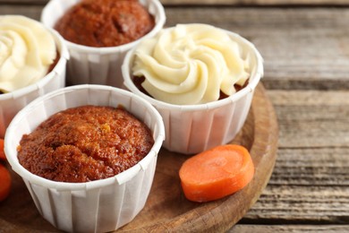 Photo of Delicious carrot muffins and fresh vegetable on wooden table, closeup