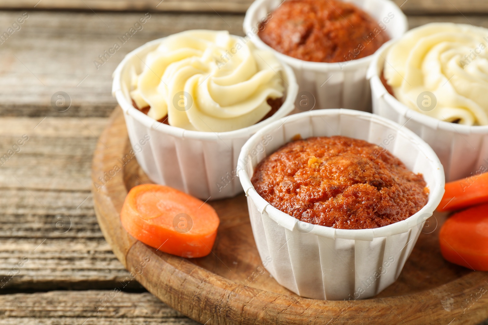 Photo of Delicious carrot muffins and fresh vegetable on wooden table, closeup