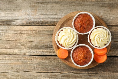 Photo of Tasty carrot muffins and fresh vegetable on wooden table, top view. Space for text