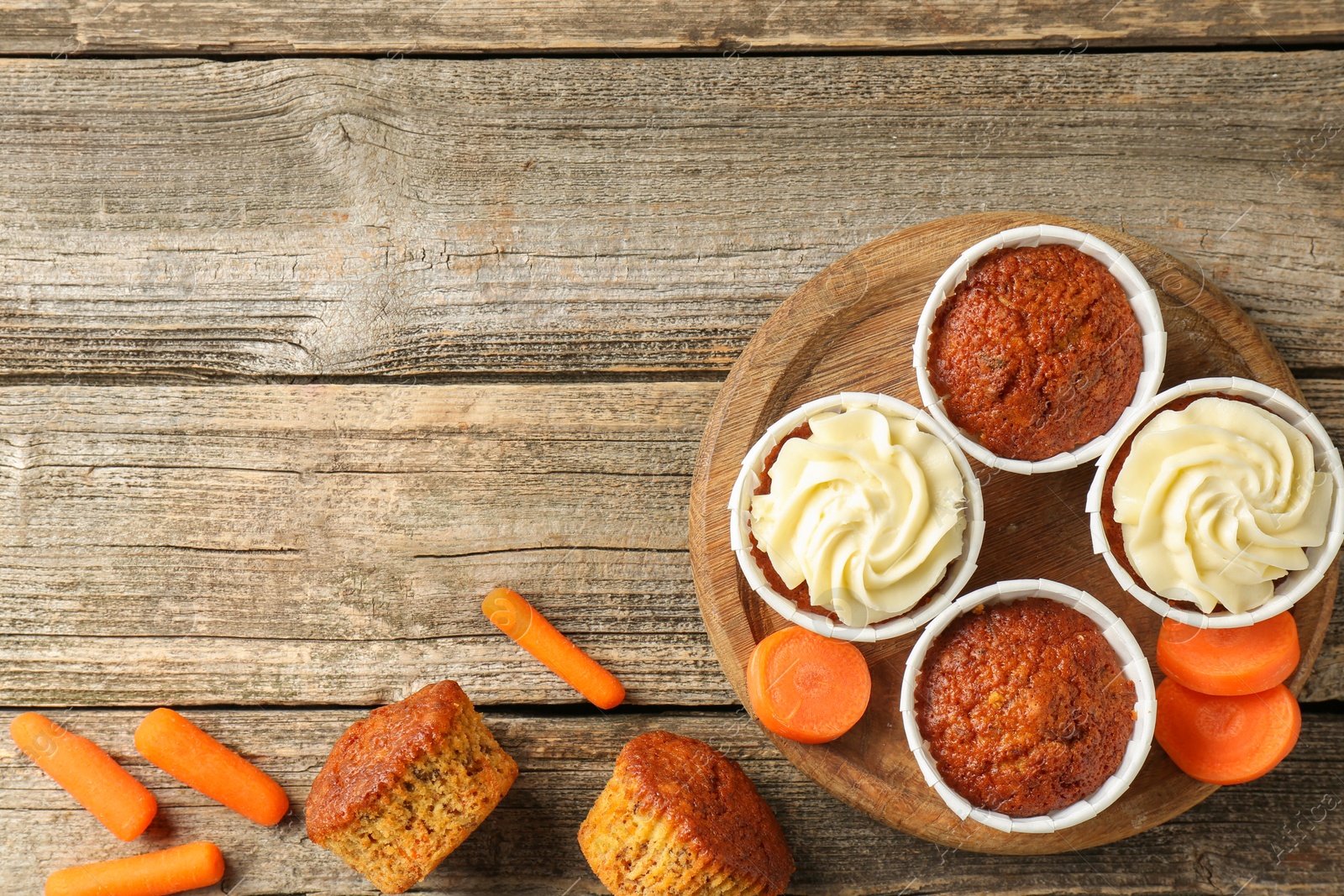 Photo of Delicious carrot muffins and fresh vegetables on wooden table, flat lay. Space for text