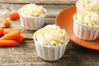 Photo of Delicious carrot muffins and fresh vegetables on wooden table, closeup