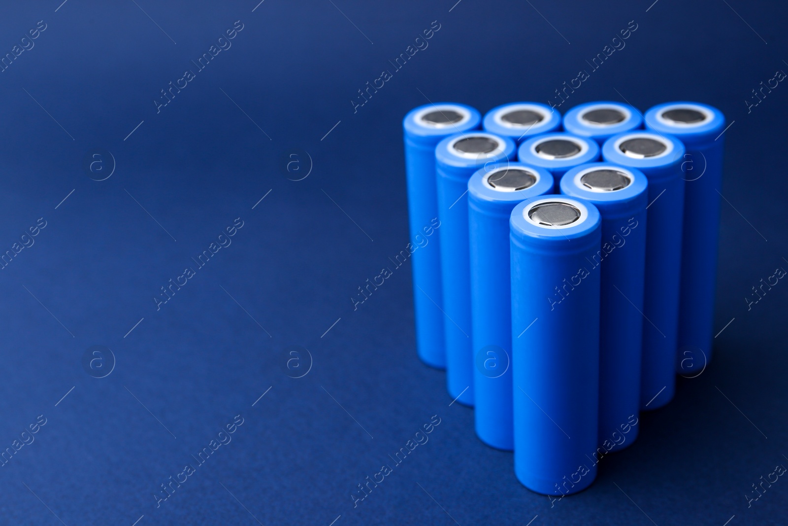 Photo of Many AA cell batteries on blue background, closeup. Space for text