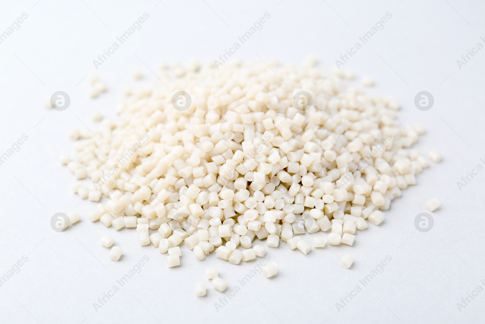 Photo of Pile of plastic granules on white background, closeup