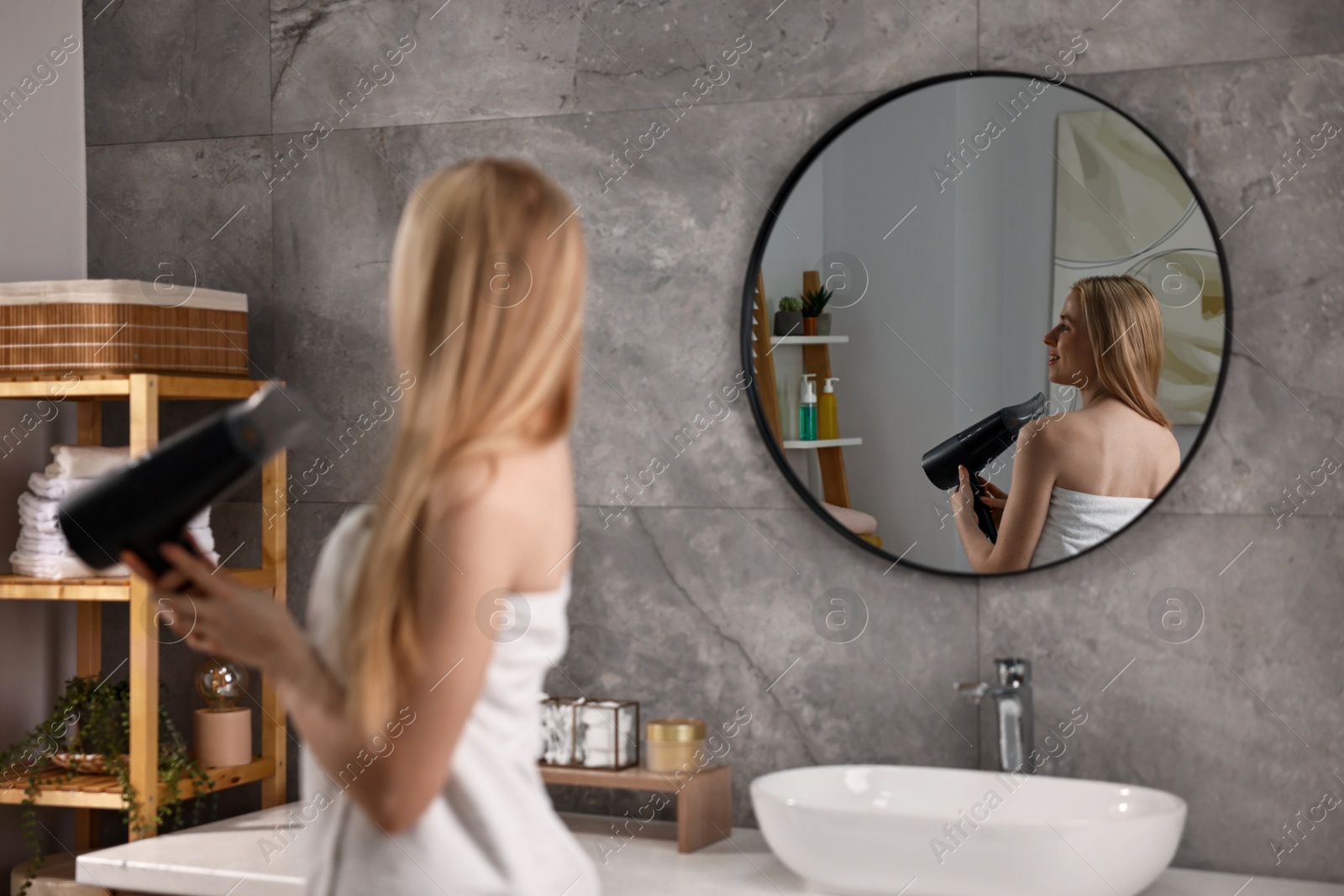 Photo of Beautiful young woman drying her hair in bathroom