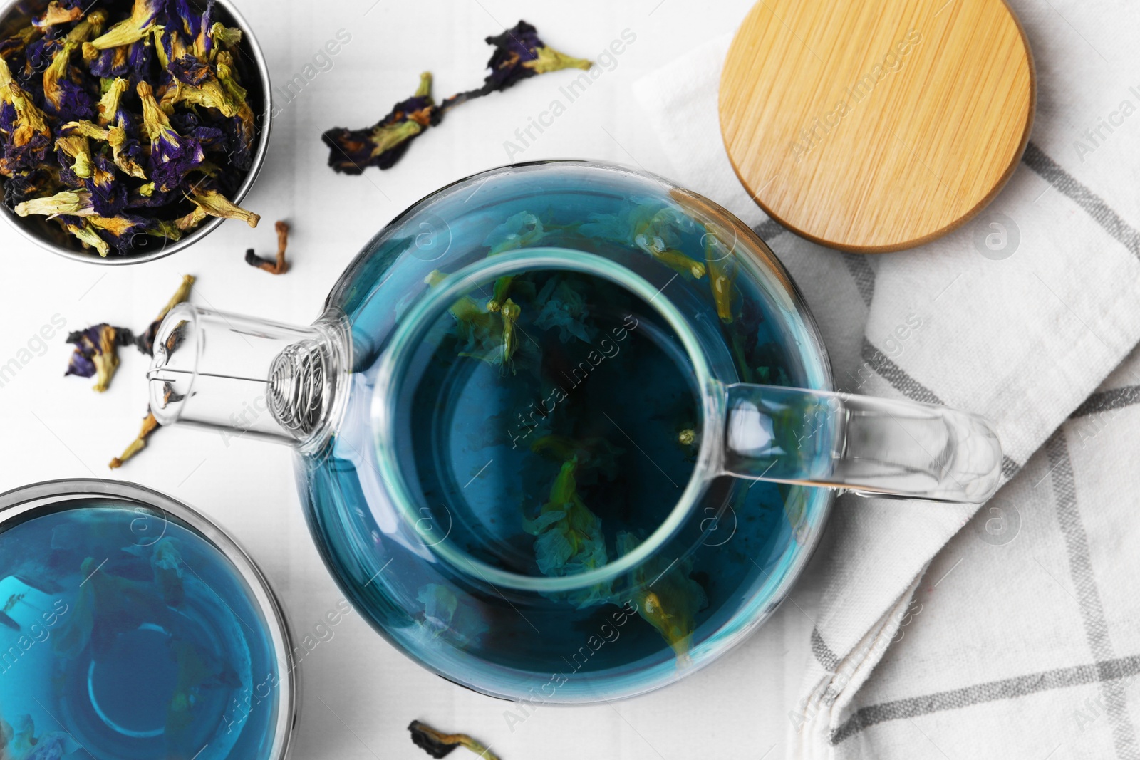 Photo of Delicious butterfly pea flower tea on white tiled table, flat lay