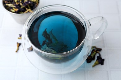 Photo of Delicious butterfly pea flower tea on white tiled table, closeup