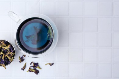 Delicious butterfly pea flower tea on white tiled table, flat lay. Space for text