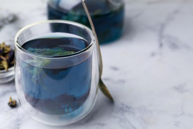 Photo of Delicious butterfly pea flower tea on white marble table, closeup. Space for text