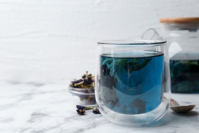 Photo of Delicious butterfly pea flower tea on white marble table. Space for text