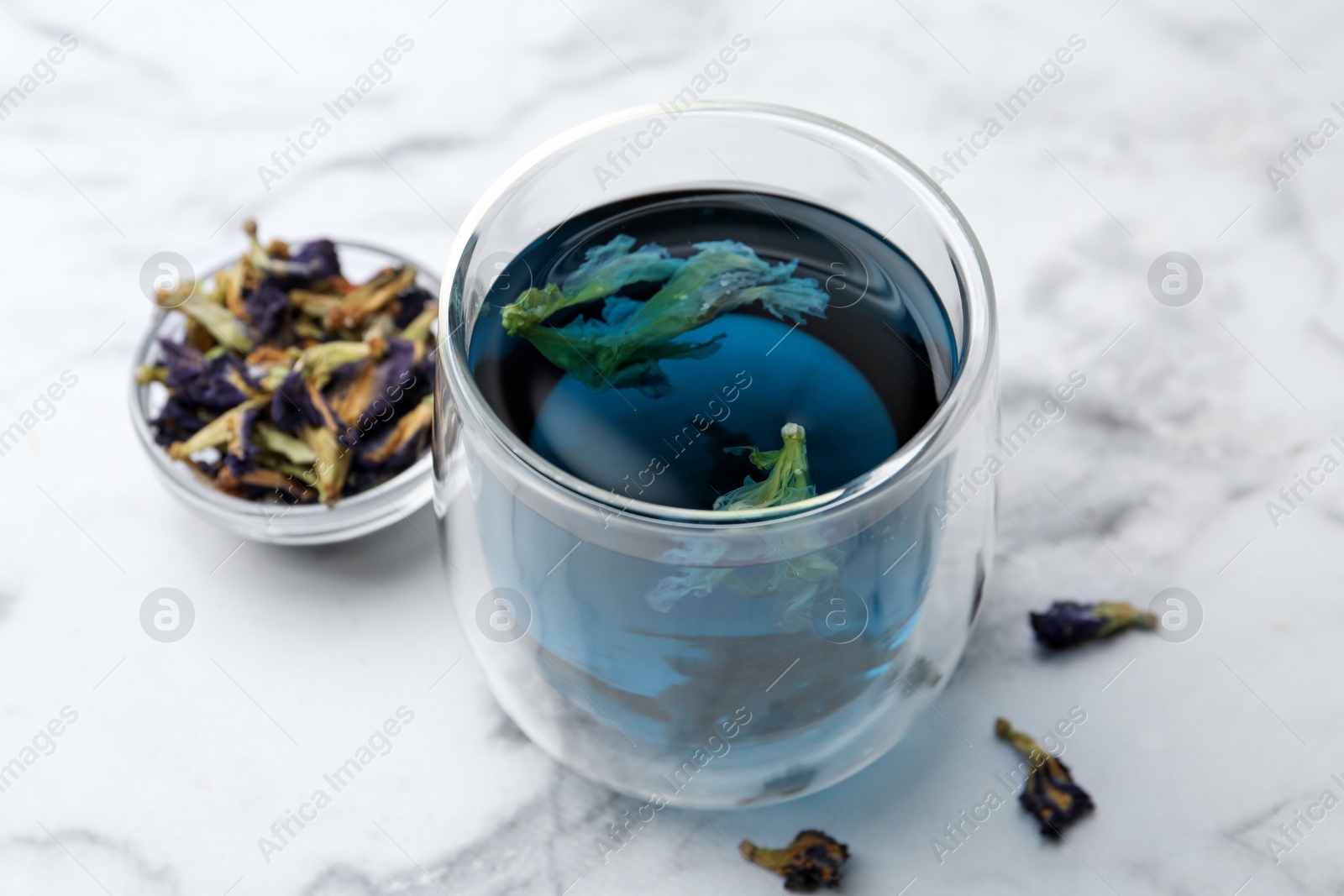 Photo of Delicious butterfly pea flower tea on white marble table, closeup