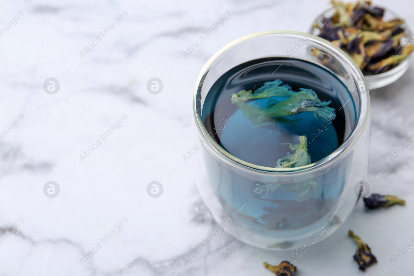 Photo of Delicious butterfly pea flower tea on white marble table, closeup. Space for text