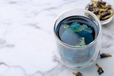 Photo of Delicious butterfly pea flower tea on white marble table, closeup. Space for text