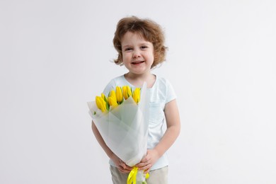 Photo of Cute little boy with bouquet of tulips on white background