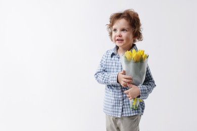 Photo of Cute little boy with bouquet of tulips on white background. Space for text