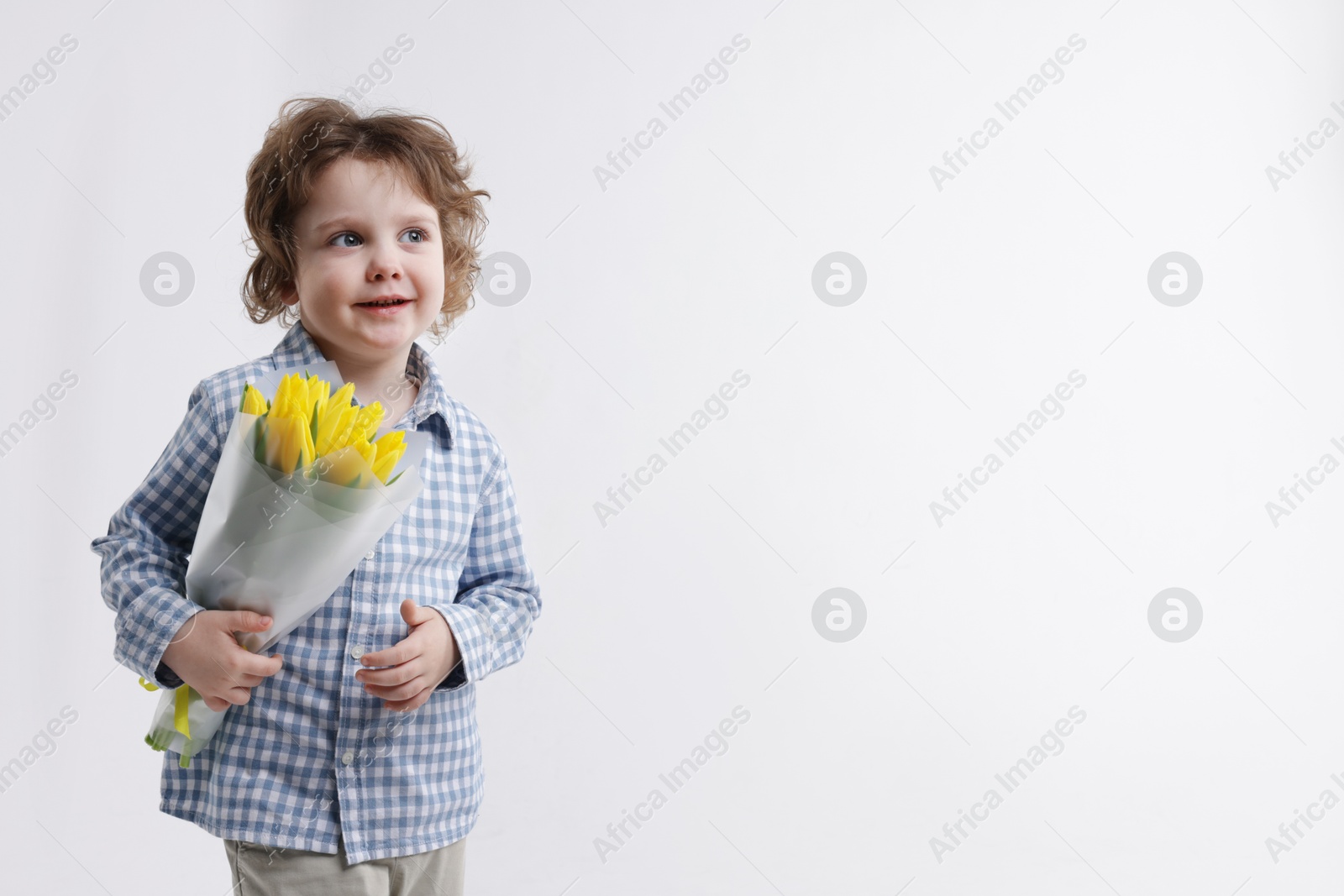 Photo of Cute little boy with bouquet of tulips on white background. Space for text