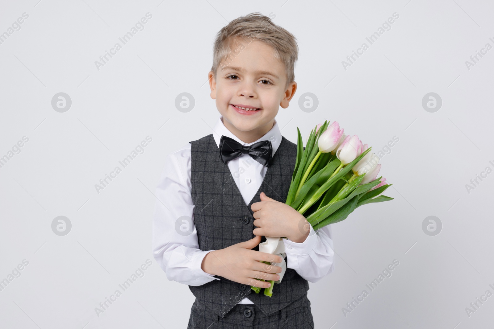 Photo of Cute little boy with bouquet of tulips on white background