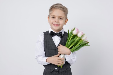 Cute little boy with bouquet of tulips on white background