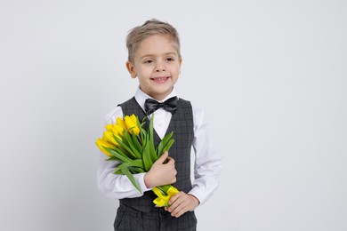 Photo of Cute little boy with bouquet of tulips on white background