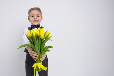 Photo of Cute little boy with bouquet of tulips on white background. Space for text