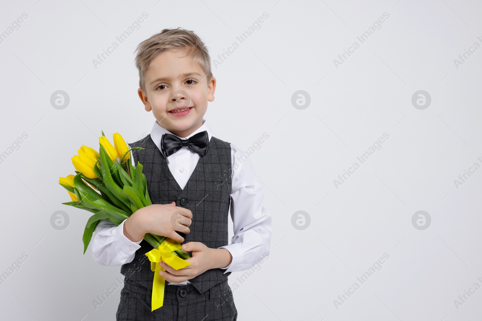 Photo of Cute little boy with bouquet of tulips on white background. Space for text