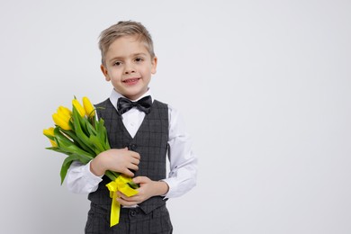 Cute little boy with bouquet of tulips on white background. Space for text