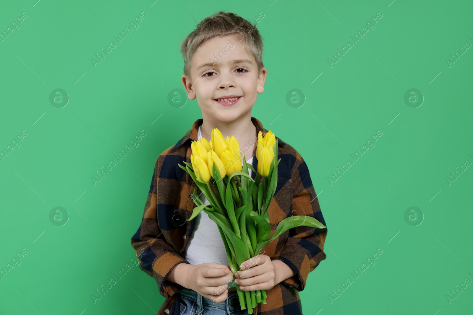 Photo of Cute little boy with bouquet of tulips on green background