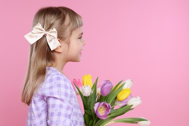 Photo of Cute little girl with bouquet of tulips on pink background. Space for text