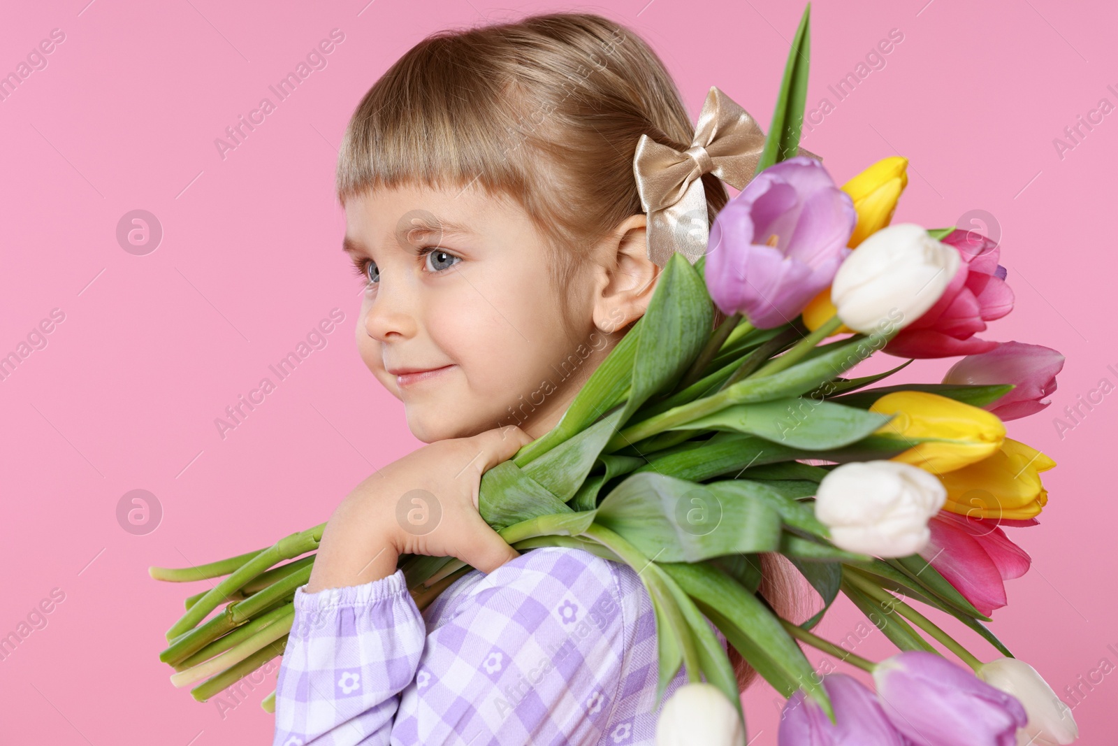 Photo of Cute little girl with bouquet of tulips on pink background