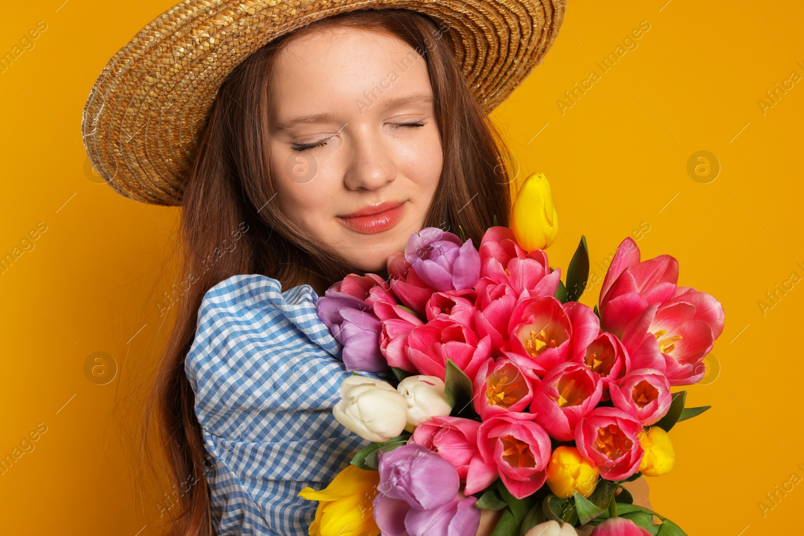 Photo of Beautiful teenage girl with bouquet of tulips on orange background