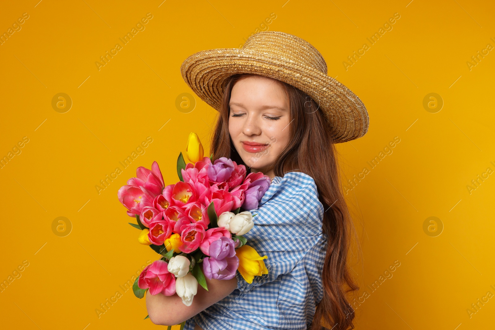 Photo of Beautiful teenage girl with bouquet of tulips on orange background