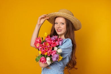 Photo of Beautiful teenage girl with bouquet of tulips on orange background