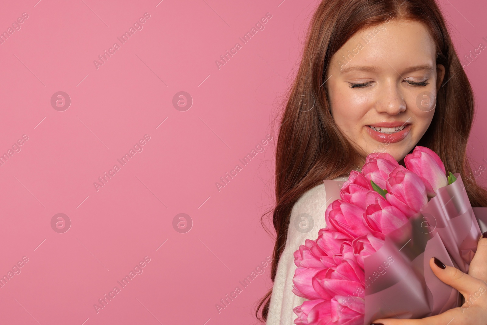 Photo of Beautiful teenage girl with bouquet of tulips on pink background, space for text