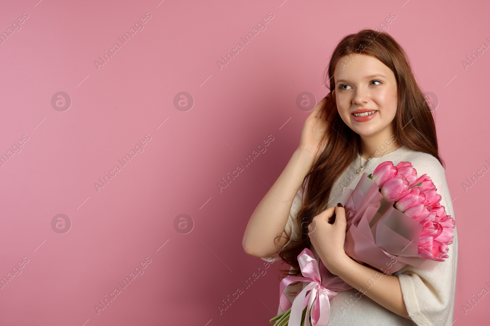 Photo of Beautiful teenage girl with bouquet of tulips on pink background, space for text