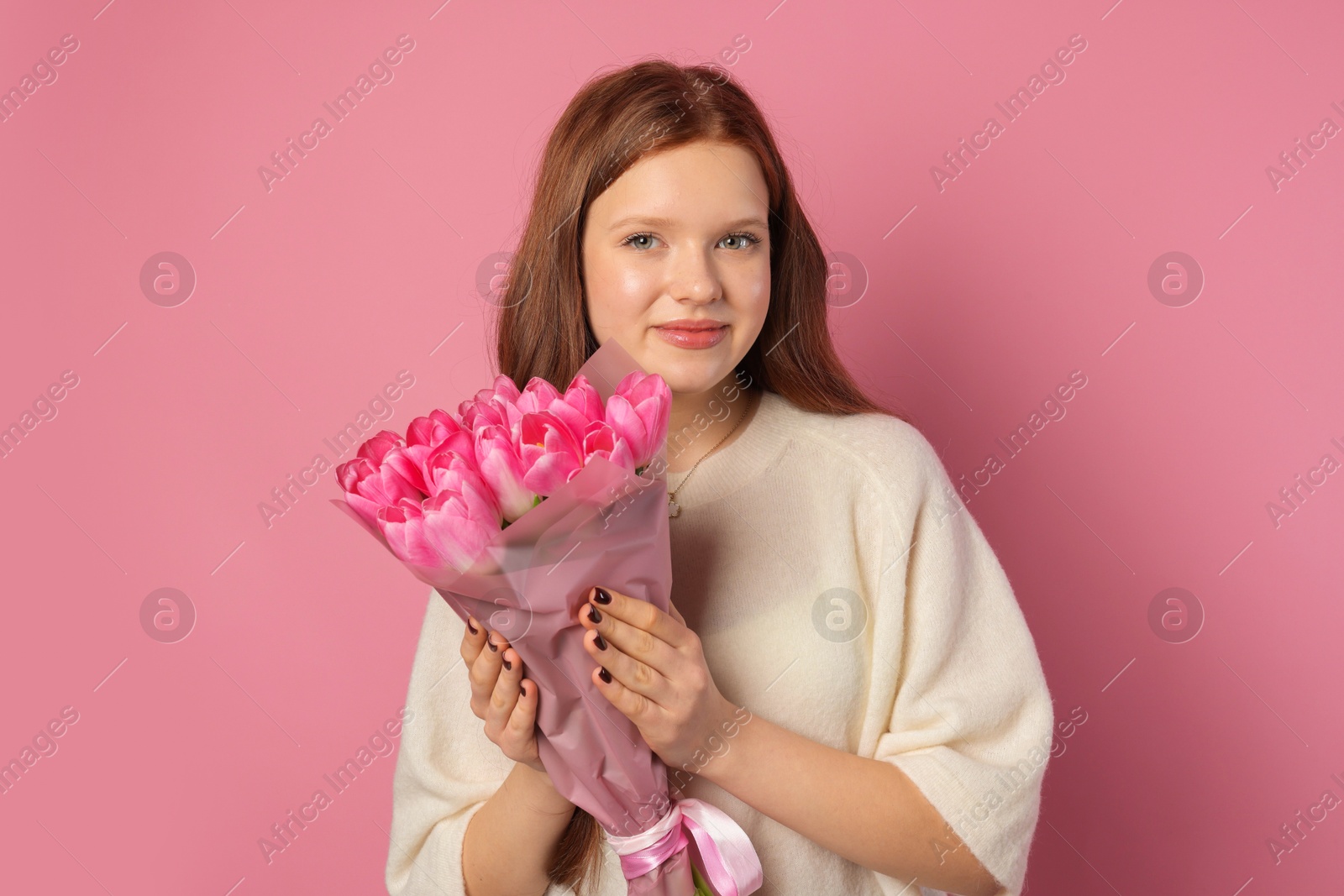 Photo of Beautiful teenage girl with bouquet of tulips on pink background