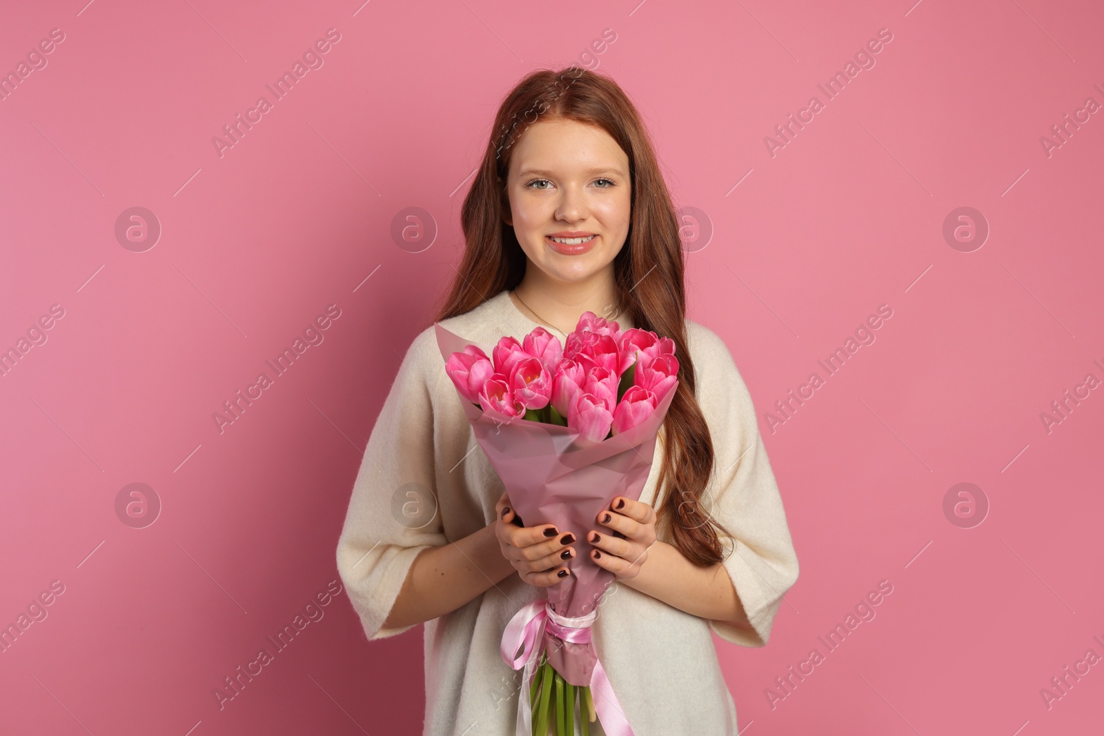 Photo of Beautiful teenage girl with bouquet of tulips on pink background