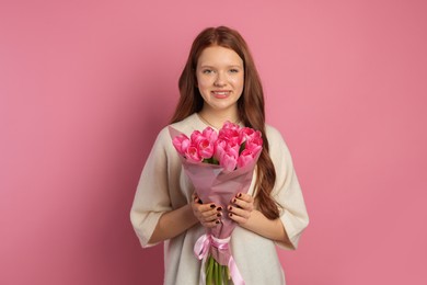 Photo of Beautiful teenage girl with bouquet of tulips on pink background