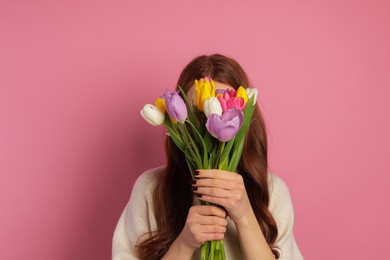 Photo of Teenage girl with bouquet of tulips on pink background