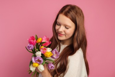 Photo of Beautiful teenage girl with bouquet of tulips on pink background