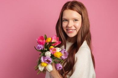 Photo of Beautiful teenage girl with bouquet of tulips on pink background